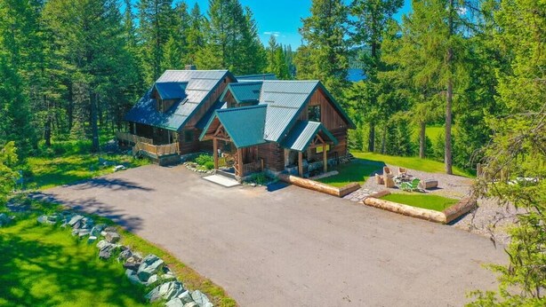 A log cabin with a metal roof, surrounded by a forest.