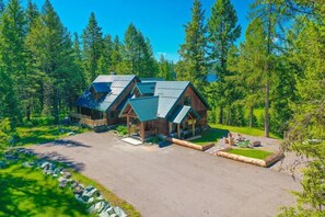 A log cabin with a metal roof, surrounded by a forest.