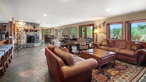A spacious living area with a stone fireplace, leather sofas, and a large rug.