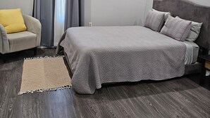 A bedroom with a bed, a ceiling fan, a window with curtains, a chair, and a rug. - NOLA Living In The Heart Of Many Attractions (New Orleans)