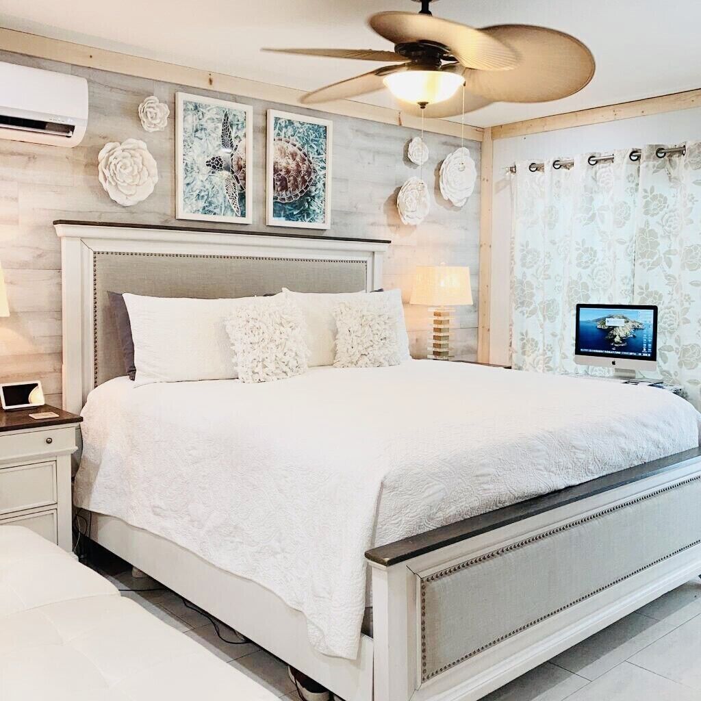 A modern bedroom with a large bed, a ceiling fan, and a TV on the wall.