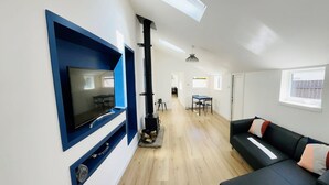 Een moderne woonkamer met een flatscreen televisie, een open haard, een bank en een eethoek.