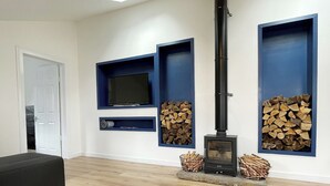 Een moderne woonkamer met een ingebouwde open haard, een televisie en houten vloeren.