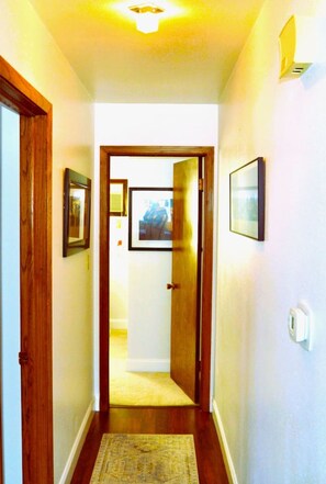 A narrow hallway with wooden doors and framed pictures on the walls.