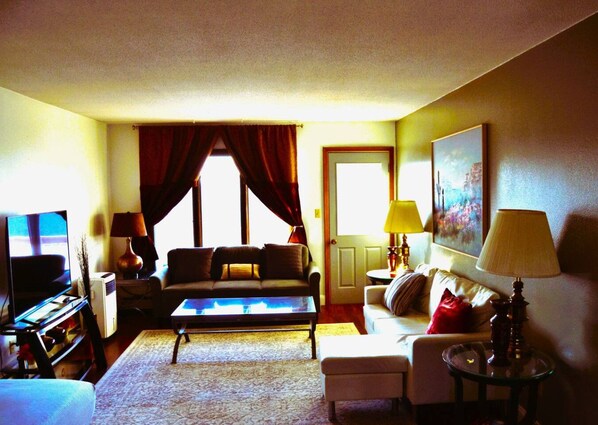 A living room with a sofa, coffee table, TV, and lamps.