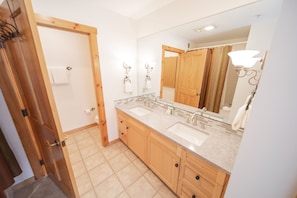 A bathroom with wooden cabinets, a double sink, a large mirror, and a towel rack. - Buffalo Lodge 8352 (Keystone)