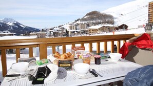 A table with breakfast items and a view of a snowy mountain town.