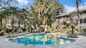 Una piscina rodeada de árboles y un edificio con balcones.