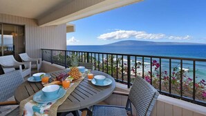 Un balcón con una mesa lista para el desayuno, con vistas a la playa y el océano.