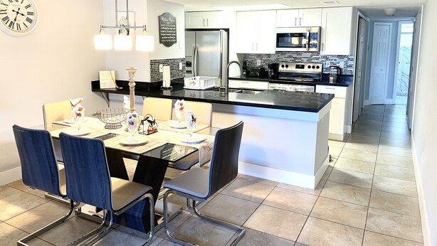 A modern kitchen with white cabinets, a stainless steel refrigerator, and a black countertop. - BEAUTIFUL LUXURY APARTMENT CLOSE DISNEY (Kissimmee)