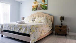A bedroom with a bed, nightstands, a ceiling fan, and a painting of a beach scene. - BEAUTIFUL LUXURY APARTMENT CLOSE DISNEY (Kissimmee)