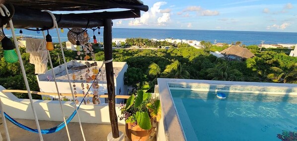 Une piscine sur le toit avec vue sur l’océan et un hamac.