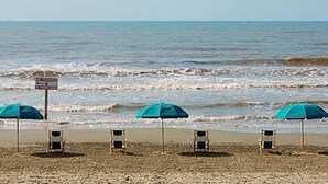 Una playa con tres sombrillas y sillas de playa.