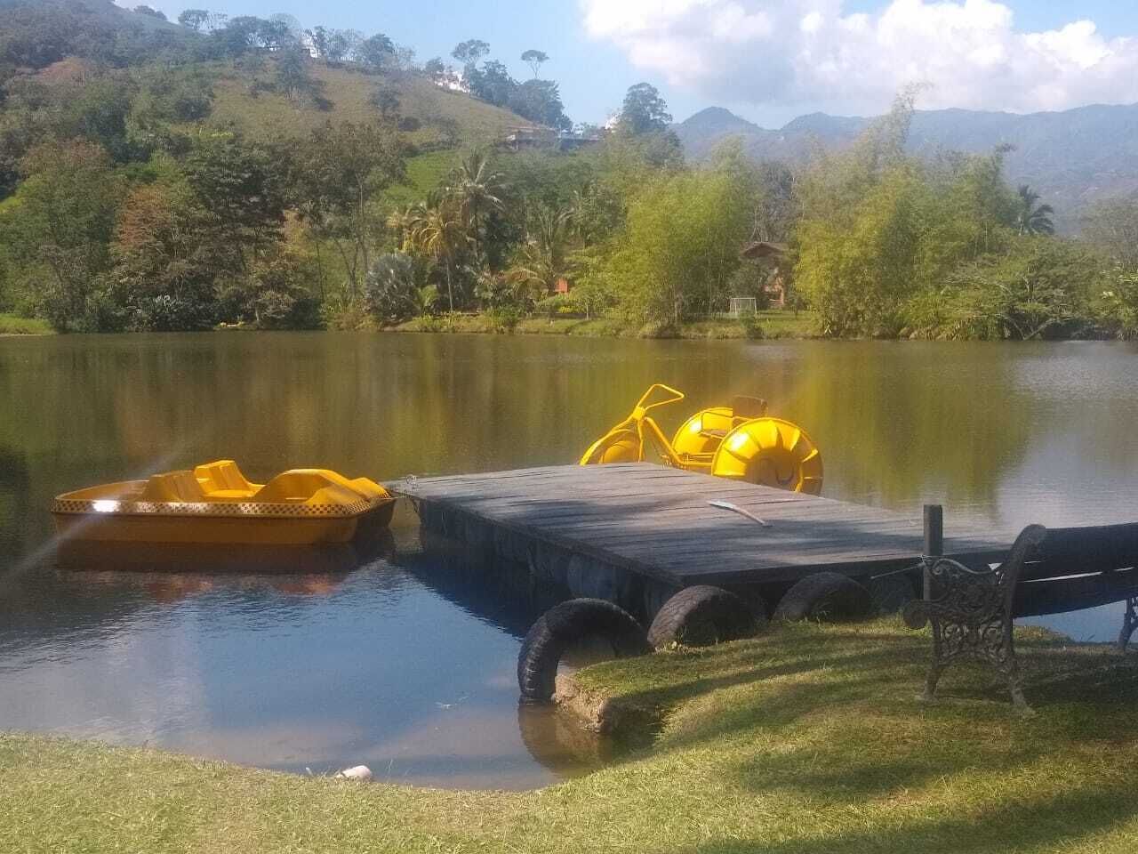 Un lago tranquilo con un muelle de madera y aros flotantes amarillos.