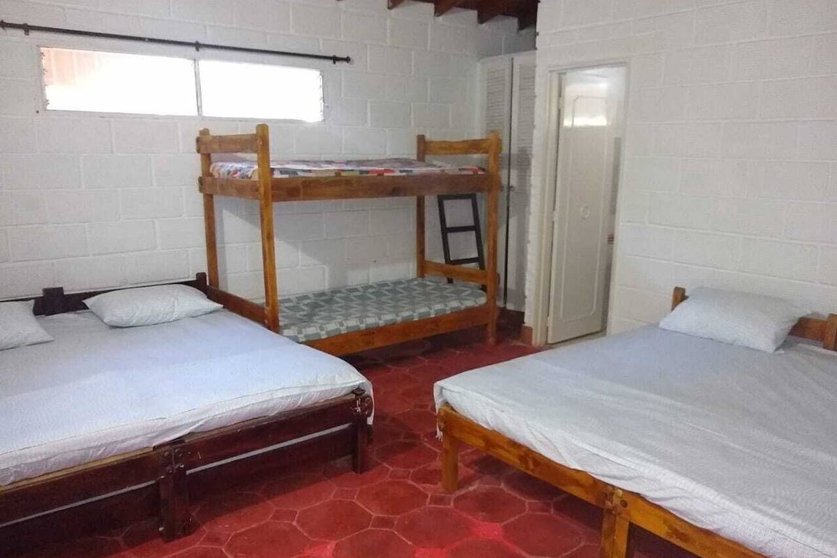 A dormitory room with bunk beds, a tiled floor, and a white brick wall.