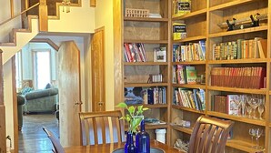 Un'ampia sala da pranzo con un tavolo e sedie in legno, circondata da librerie piene di libri e oggetti decorativi.