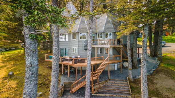 Una terrazza in legno a più livelli con scale che conducono a un balcone, immersa tra gli alberi.