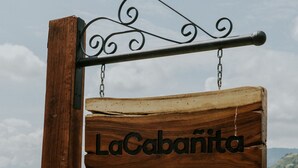 A wooden sign with the name "LaCabanita" hanging on a metal post. - Cabin in Private Forest (MORELIA)