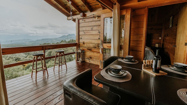 A wooden deck with a table set for dining, overlooking a mountainous landscape. - Cabin in Private Forest (MORELIA)