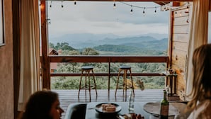 A wooden deck with two stools and a table, overlooking a mountainous landscape. - Cabin in Private Forest (MORELIA)