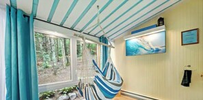 A relaxing room with a hammock, a large window, and a painting on the wall. - Tremblant-Mont Blanc/SPA/Intimacy (St-Faustin lac carré)