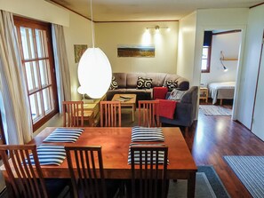 A dining area with a wooden table and chairs, a sofa, and a lamp.
