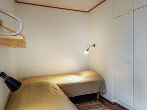 Et lille rum med en seng, et skab og en hængende lampe.