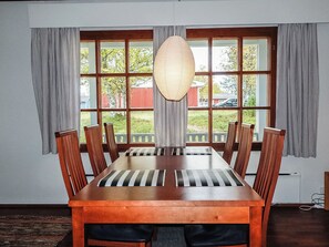 Un comedor con una gran mesa de madera, seis sillas y una lámpara colgante.