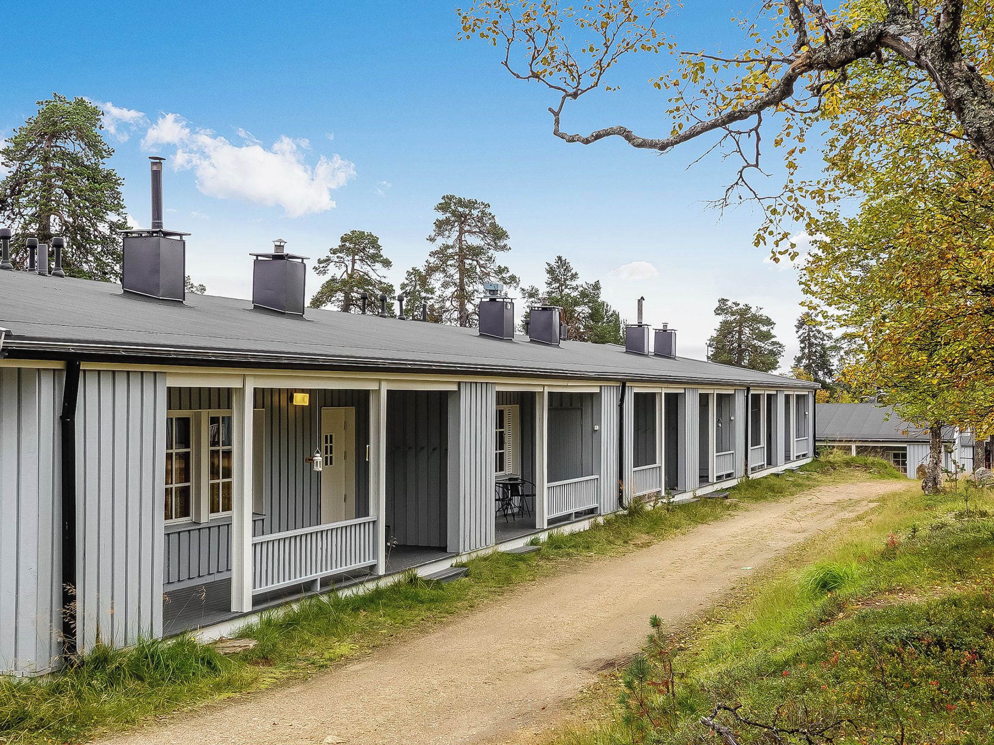 Een rij vakantiehuisjes met aanbouwde veranda's, elk met een schoorsteen.