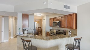 A modern kitchen with granite countertops, wooden cabinets, and stainless steel appliances. -      Breathtaking Oceanfront Condo with stunning  Panoramic Views.  (Ormond Beach)