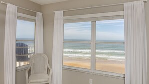 A room with a view of the beach, a chair, and a window with white curtains. -      Breathtaking Oceanfront Condo with stunning  Panoramic Views.  (Ormond Beach)