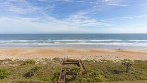 A beach with a wooden boardwalk leading to the shore, surrounded by vegetation. -      Breathtaking Oceanfront Condo with stunning  Panoramic Views.  (Ormond Beach)