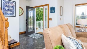 A modern interior with a wooden staircase, a beige sofa, and a welcome sign to the house. - Open year round for adventure and relaxation.  Cozy winter escape less than 20 minutes from Crystal Mountain! (Frankfort)