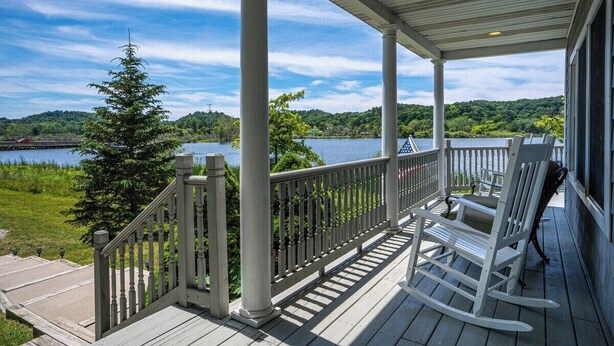 A wooden deck with a railing, overlooking a lake and forested area. - Open year round for adventure and relaxation.  Cozy winter escape less than 20 minutes from Crystal Mountain! (Frankfort)