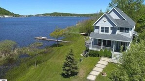 A two-story house with a porch, located near a lake with a dock. - Open year round for adventure and relaxation.  Cozy winter escape less than 20 minutes from Crystal Mountain! (Frankfort)