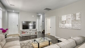 A modern living room with a flat-screen TV, a glass coffee table, and a gray sofa. - The Cloud9: Stylish, spacious and comfort at its finest (Las Vegas)