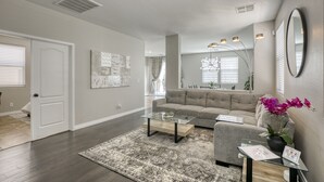 A modern living room with a grey sofa, a glass coffee table, and a large mirror. - The Cloud9: Stylish, spacious and comfort at its finest (Las Vegas)