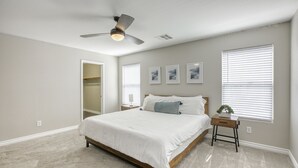 A bedroom with a bed, a ceiling fan, a nightstand, a window with blinds, and a closet. - The Cloud9: Stylish, spacious and comfort at its finest (Las Vegas)