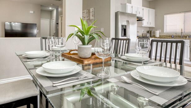 A modern dining area with a glass table set for six, surrounded by chairs. - The Cloud9: Stylish, spacious and comfort at its finest (Las Vegas)