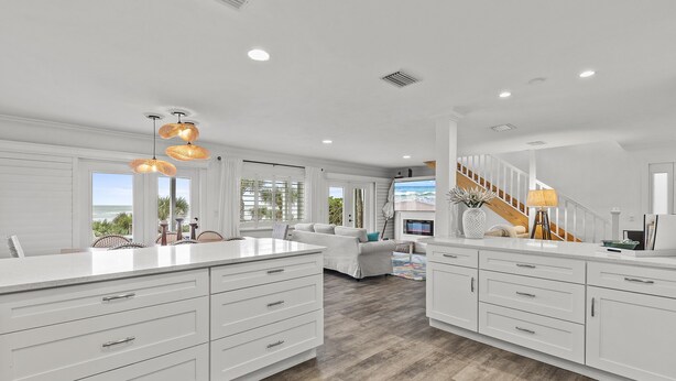 A spacious kitchen with white cabinetry, a large island, and pendant lighting.