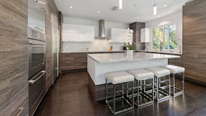 A modern kitchen with a large island, stainless steel appliances, and bar stools.
