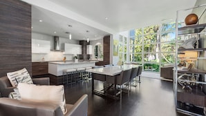 A modern kitchen with a central island, bar stools, and a dining area with a large table.