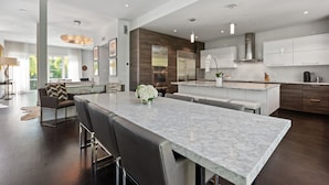 A modern kitchen with a large island, dark wood cabinets, and stainless steel appliances.