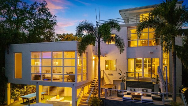 A modern two-story house with a swimming pool, outdoor seating, and a staircase leading to the upper level.