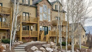 A multi-story building with a stone facade, wooden balconies, and a central entrance with a green door. - Mountain Condo Near Snowbasin, Powder & Nordic (Eden)