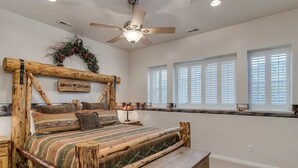 A rustic bedroom with a wooden bed frame, a ceiling fan, and a window with blinds. - Mountain Condo Near Snowbasin, Powder & Nordic (Eden)