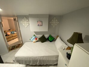 A bedroom with a large bed, a bedside table, a lamp, and a decorative wall hanging.