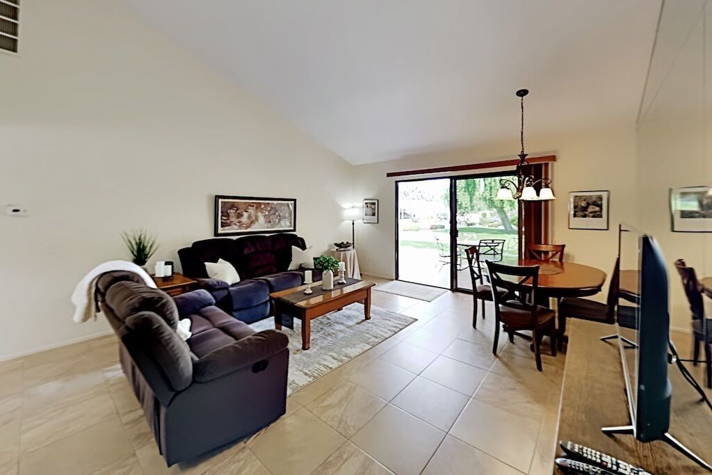 A living room with a sofa, coffee table, and a dining area with chairs and a table.