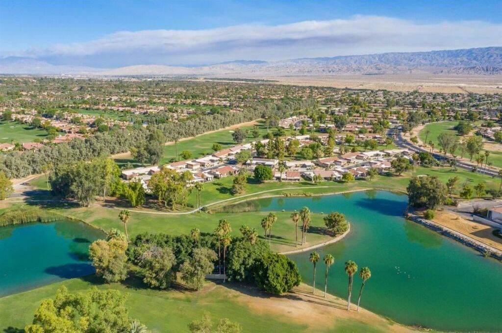 Un parcours de golf avec un étang, entouré de bâtiments résidentiels et de verdure.