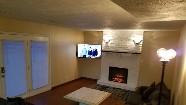 A living room with a fireplace, a television, and a sofa. - Spacious SW Omaha Home Near I-80, Garage Game Room, Family-Friendly, Safe Area! (Omaha)